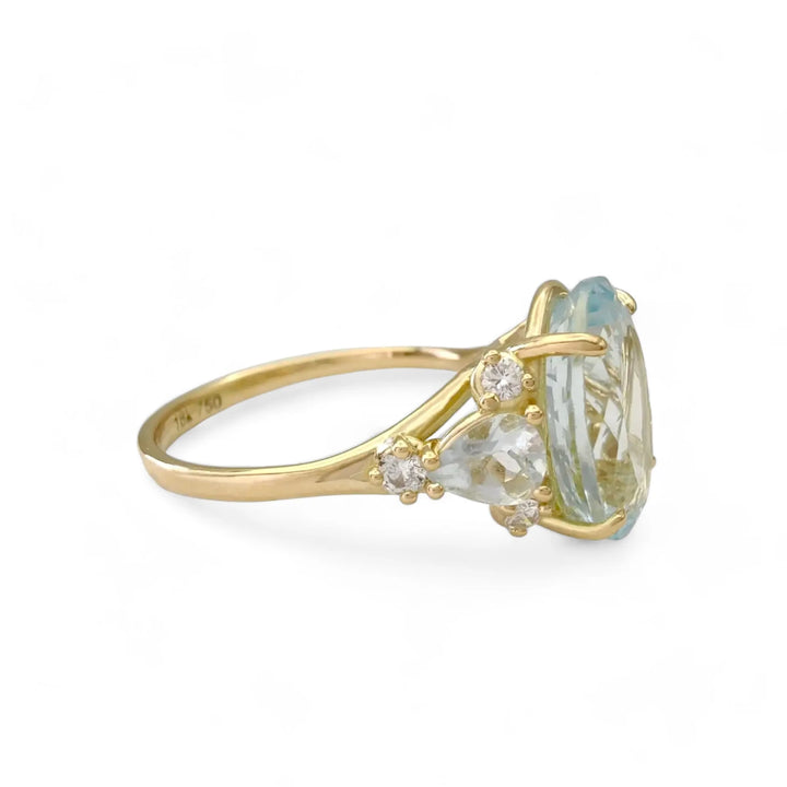 Right side view of an elegant engagement ring in 18K yellow gold featuring a central oval aquamarine, additional pear-shaped aquamarine, and diamonds