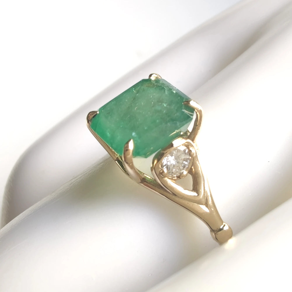 Elegant 18K yellow gold engagement ring with a central octagon emerald and diamond accents displayed on a mannequin hand