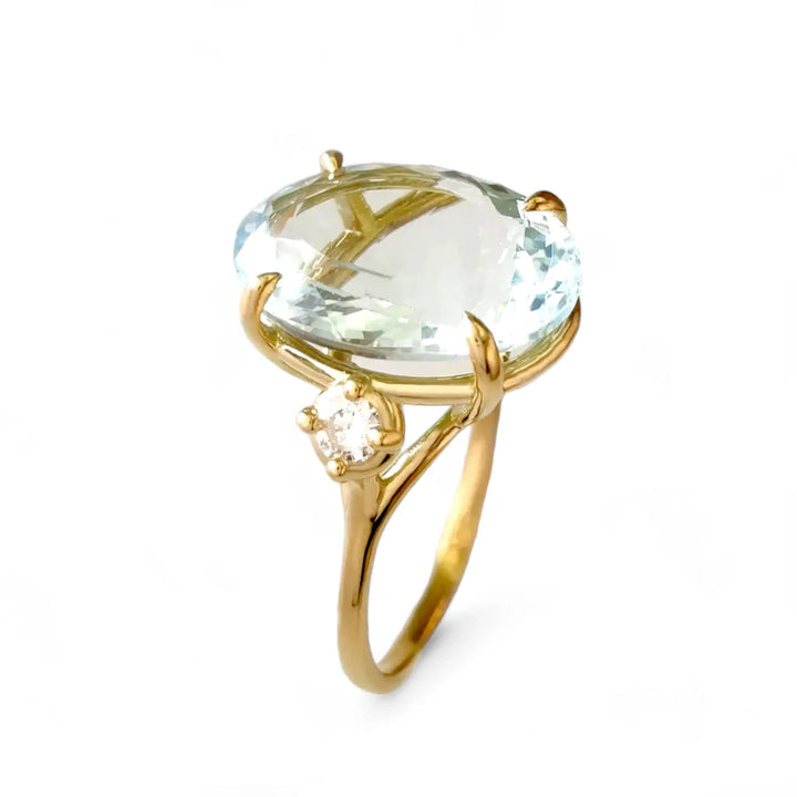 Vertical perspective view of a handcrafted 18K yellow gold three-stone ring featuring an oval aquamarine centerpiece and a brilliant-cut diamond on each side, perfect for engagements or Christmas gifts