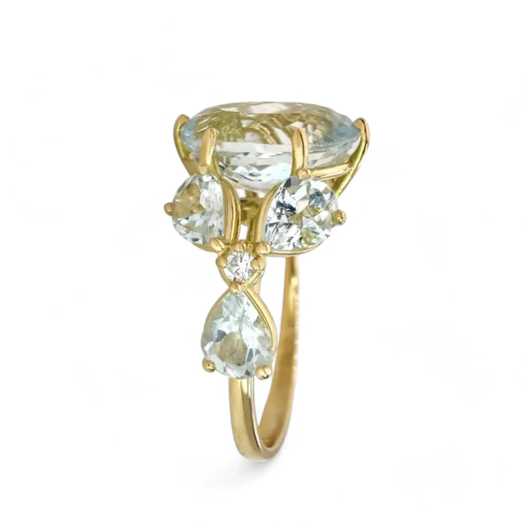 Vertical perspective view of a handcrafted women’s ring featuring a large oval aquamarine centerpiece, marquise aquamarines, and diamond floral accents in a sculptural design