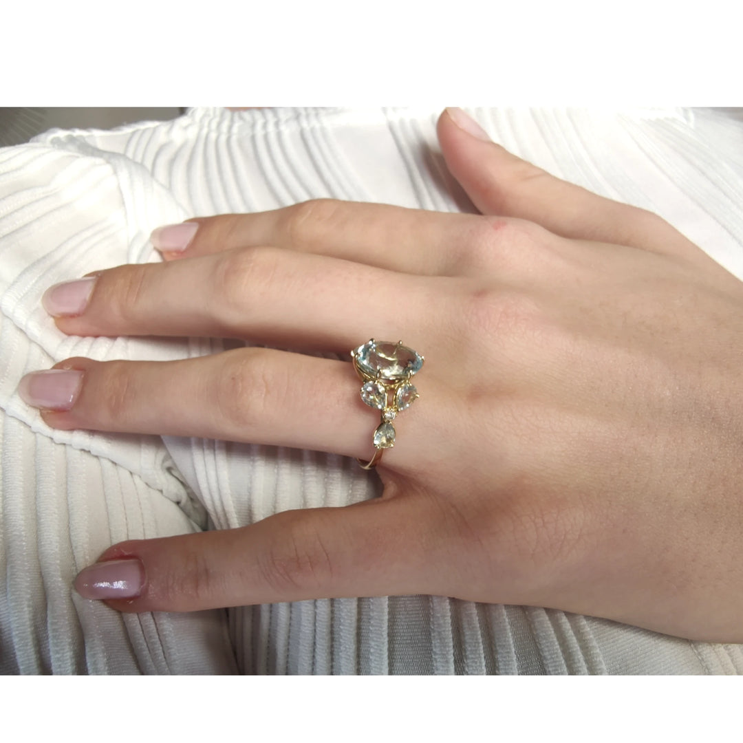 Unique oval aquamarine and diamond floral ring displayed on a model’s hand in an elegant pose, showcasing its artistic design