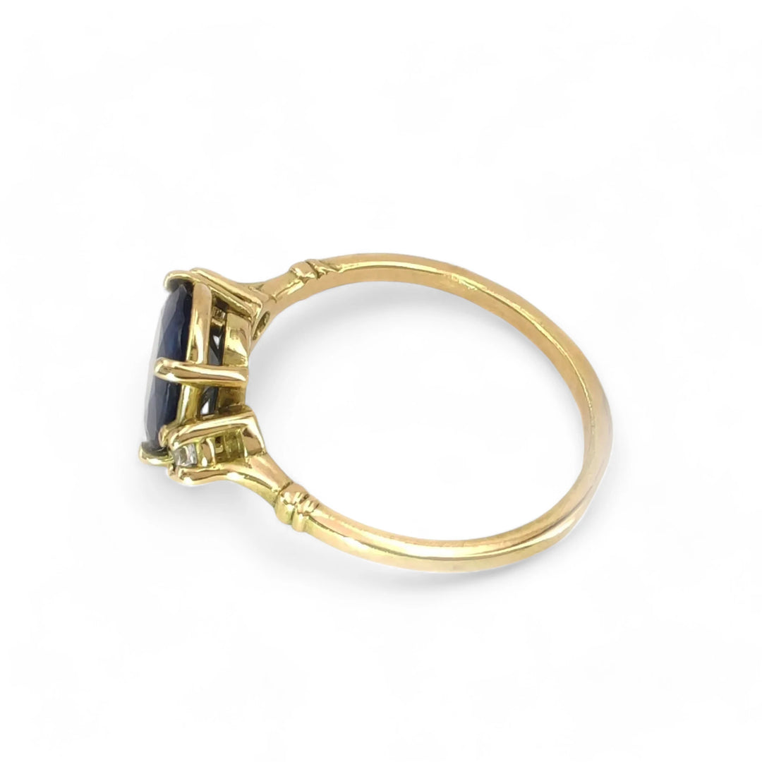 Left side view of an elegant three-stone sapphire engagement ring in 18K yellow gold with diamond detailing