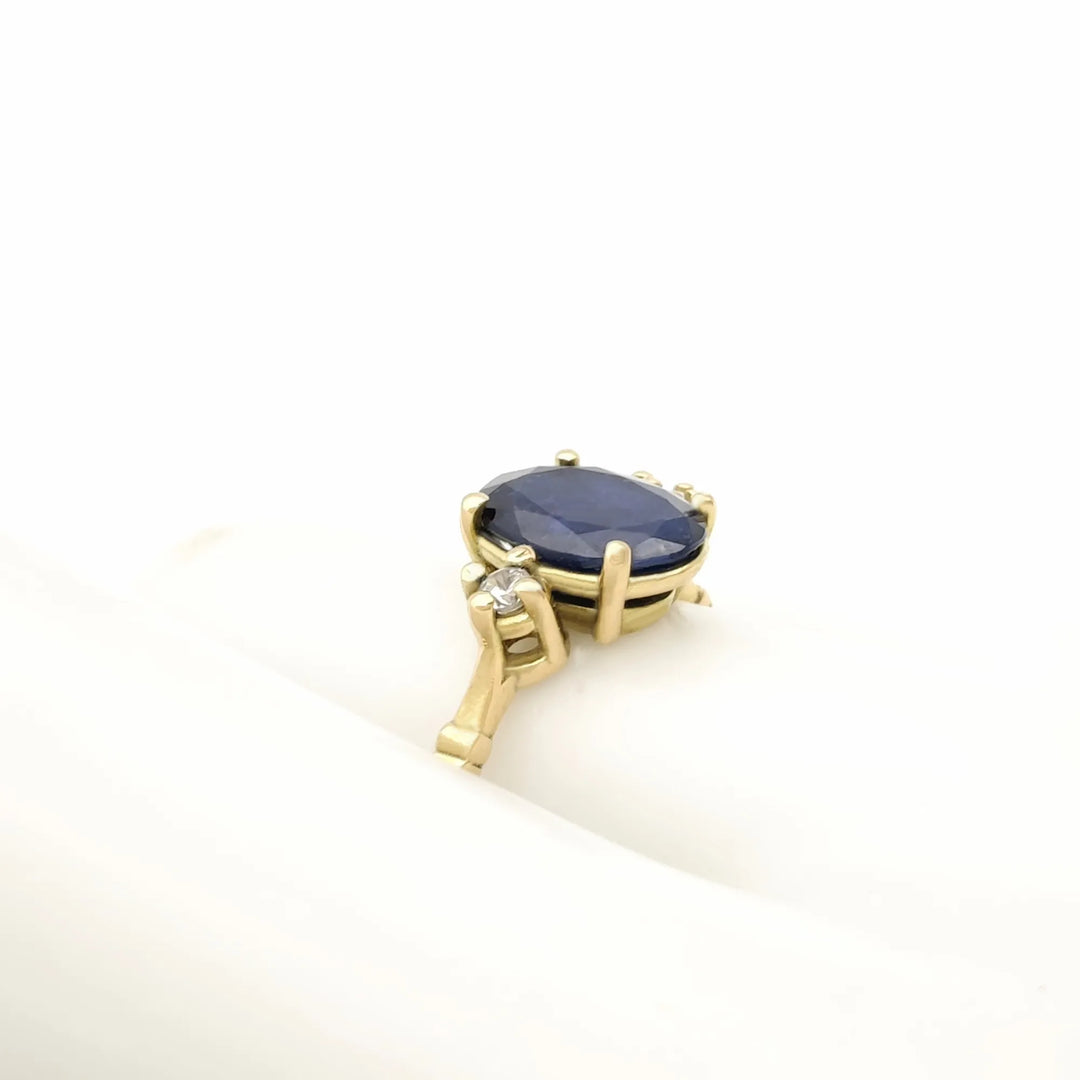 Left side pose view of a handcrafted 18K yellow gold three-stone ring featuring a central sapphire and diamond accents, ideal for Black Friday gifting