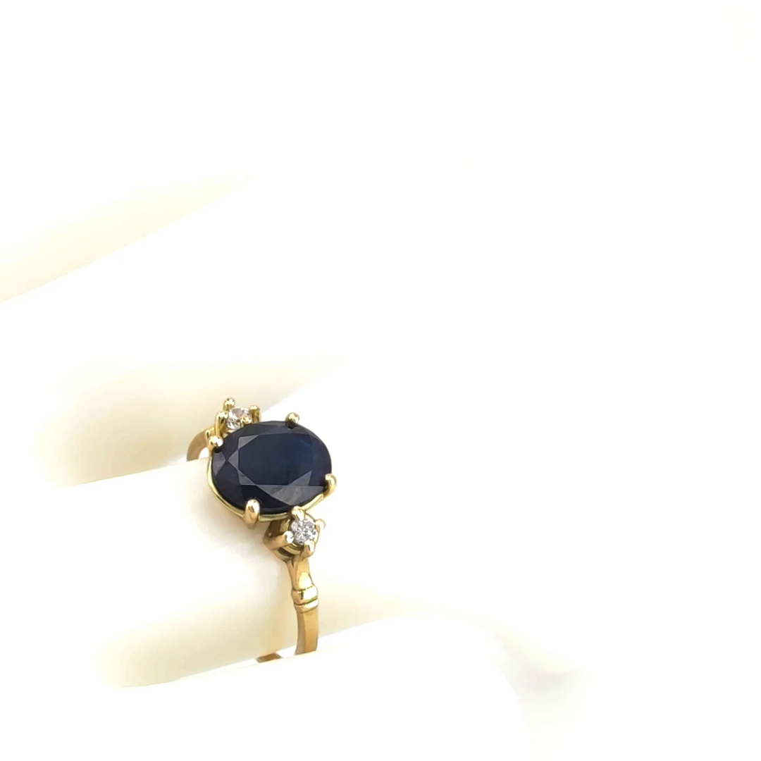 Top view of a stunning sapphire engagement ring in 18K yellow gold with a central oval sapphire and diamond side stones, displayed on a mannequin