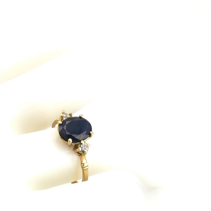 Top view of a stunning sapphire engagement ring in 18K yellow gold with a central oval sapphire and diamond side stones, displayed on a mannequin