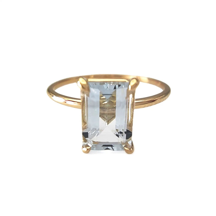 Front view of a minimalist 18K yellow gold solitaire ring with a central aquamarine