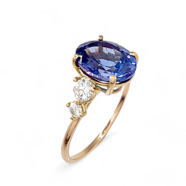 Perspective view of a 14K yellow gold women’s ring with an oval Tanzanite centerpiece and two brilliant-cut diamonds on each side