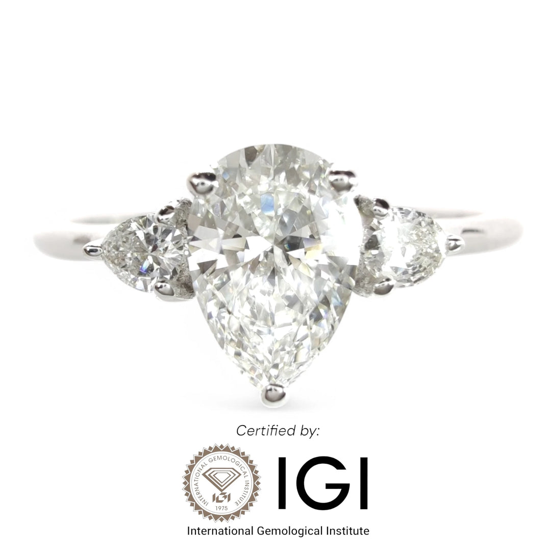 Three-stone diamond engagement ring in white gold with pear-shaped center stone and tapered band