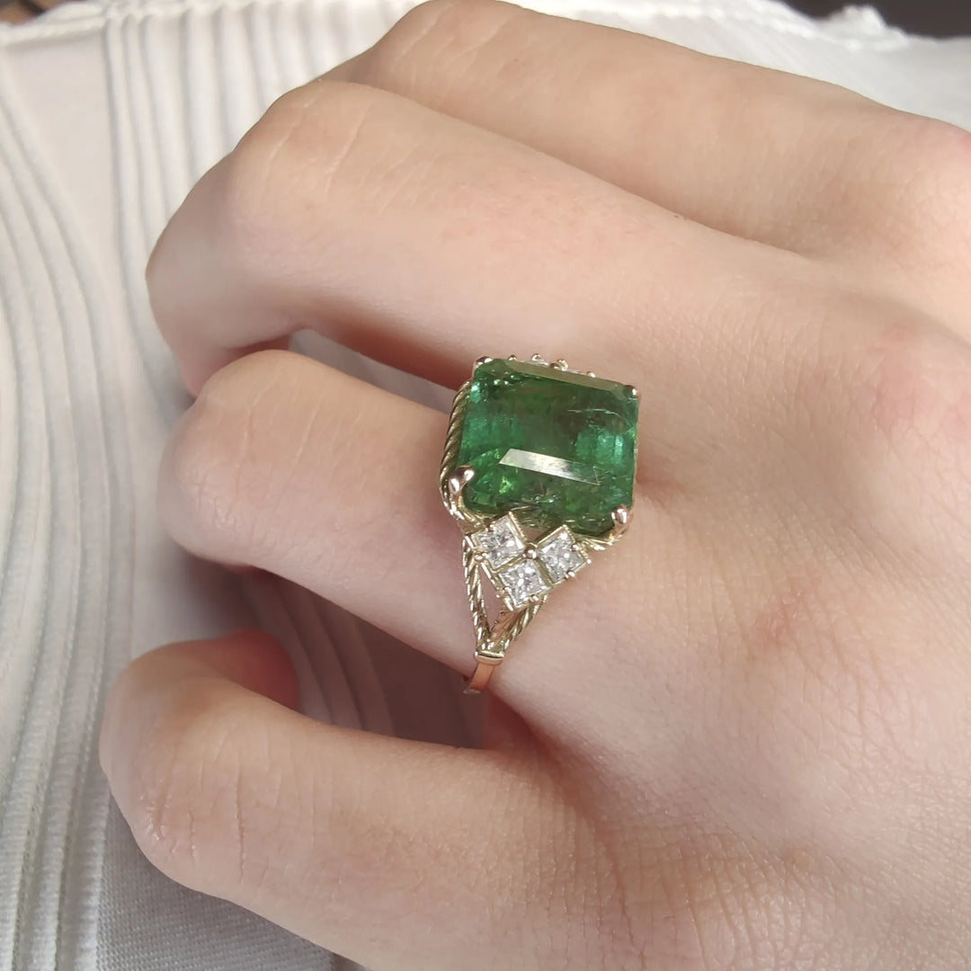 View of a model’s hand wearing a 14K yellow gold vintage engagement ring, showcasing the green tourmaline and princess-cut diamonds, perfect for proposals or as a luxurious gift for a mother, girlfriend, or friend