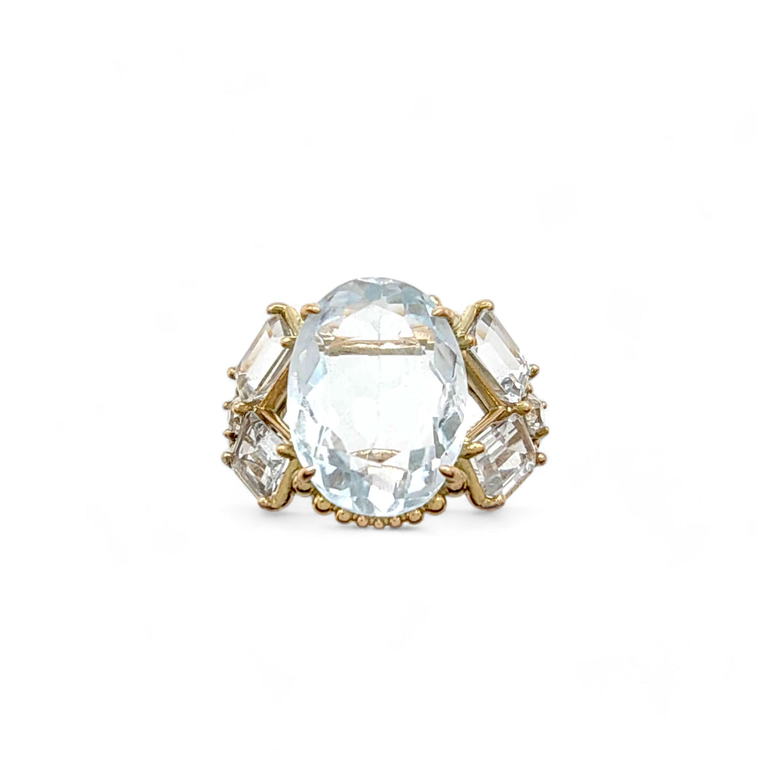 Front view of a bold vintage-inspired ring with an oval aquamarine centerpiece, emerald-cut aquamarines, and brilliant diamonds in 14K yellow gold